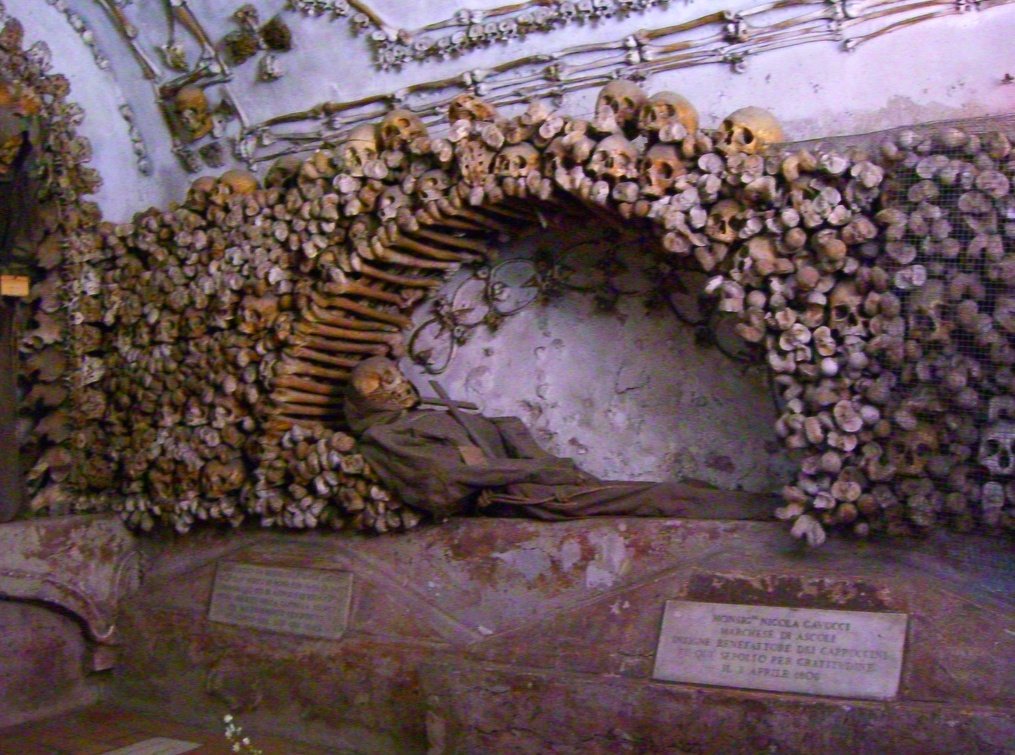 The skeletons, which are dressed in robes staring from the walls and in the background, there are hundreds of anonymous skulls of those who died long ago. Image via italianwriter.it