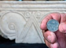 A five-shekel coin juxtaposed with a column head found at Armon HaNatziv. Image credit: Yaniv Berman, Israel Antiquities Authority