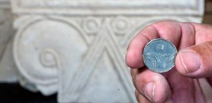 A five-shekel coin juxtaposed with a column head found at Armon HaNatziv. Image credit: Yaniv Berman, Israel Antiquities Authority