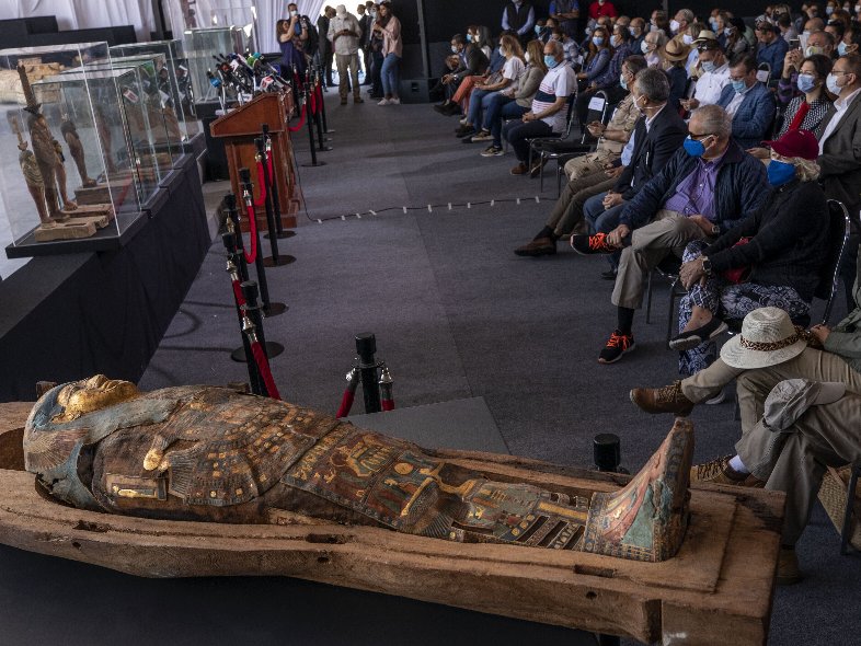 People look at ancient sarcophagi discovered in a vast necropolis in Saqqara, Giza, Egypt, Saturday, Nov. 14, 2020. Egyptian antiquities officials on Saturday announced the discovery of at least 100 ancient coffins, some with mummies inside, and around 40 gilded statues south of Cairo. (AP Photo/Nariman El-Mofty)