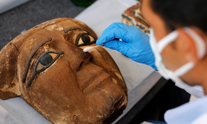 An archaeologist works on an artifact, around 2,500 years old, from the newly discovered burial site near Egypt's Saqqara necropolis, during a presentation in Giza, Egypt November 14, 2020. REUTERS