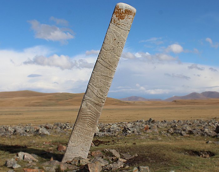 A leaning Deer Stone placed in front of dozens of small stone mounds containing ritually-sacrificed horse burials at the Bronze Age monument site of Ikh Tsagaanii Am, Bayankhongor Province, central Mongolia Credit: William Taylor